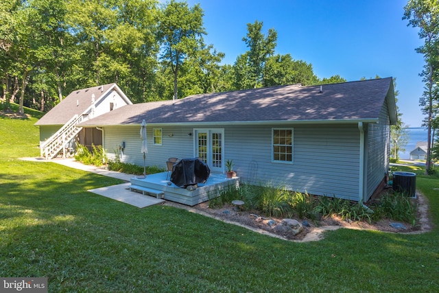 rear view of house featuring a wooden deck, a lawn, and roof with shingles