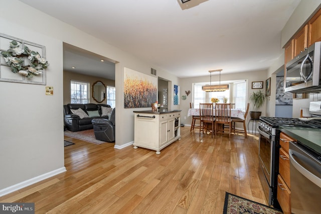 kitchen with dark countertops, a healthy amount of sunlight, light wood-style flooring, and appliances with stainless steel finishes