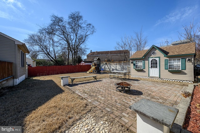 view of yard featuring a trampoline, a patio, a fire pit, and fence