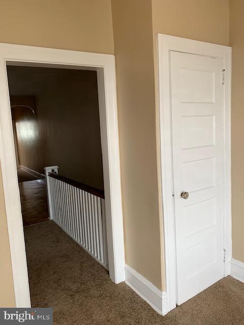 hall with dark carpet and baseboards