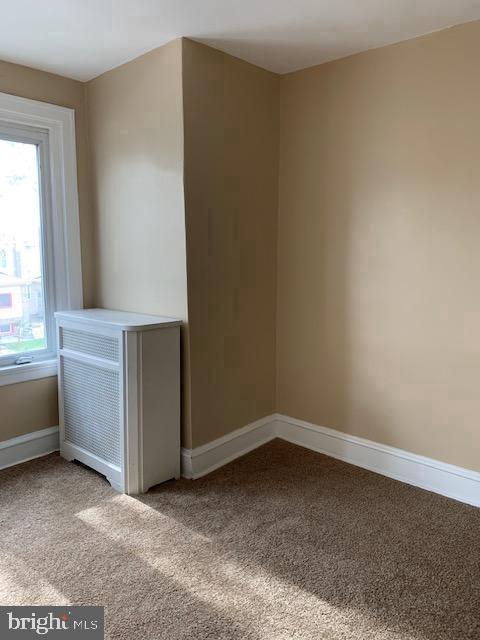 carpeted empty room featuring baseboards