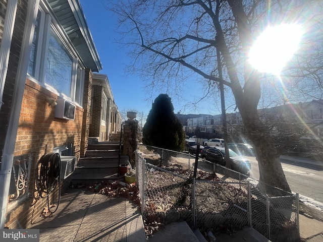 view of property exterior featuring fence and brick siding