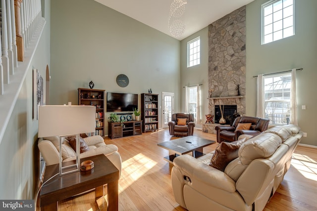 living room featuring high vaulted ceiling, light wood-type flooring, and a stone fireplace