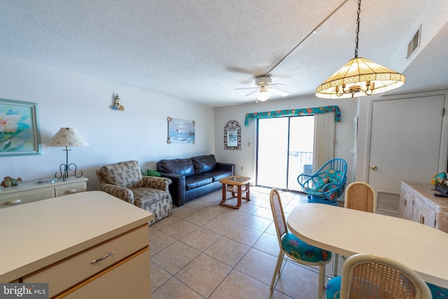 living area with light tile patterned floors, ceiling fan, a textured ceiling, and visible vents