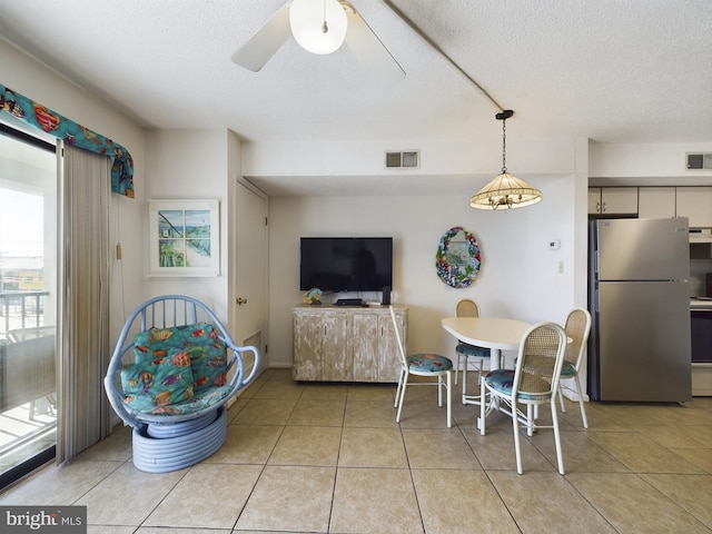 dining area featuring light tile patterned floors, ceiling fan, visible vents, and a textured ceiling