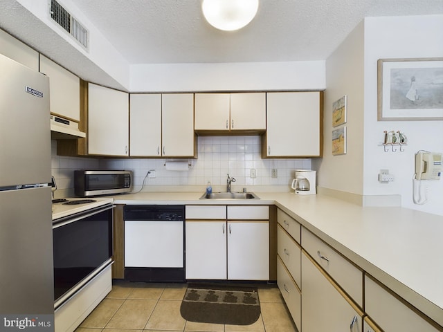 kitchen featuring decorative backsplash, stainless steel appliances, light countertops, under cabinet range hood, and a sink