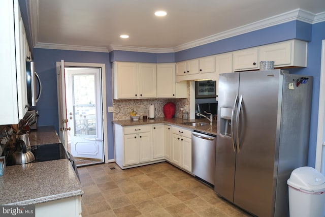 kitchen featuring crown molding, decorative backsplash, appliances with stainless steel finishes, white cabinets, and a sink