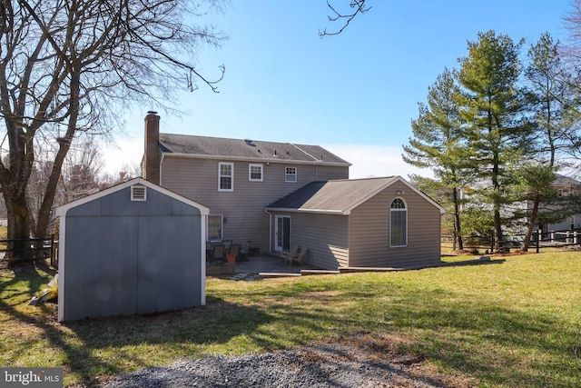 rear view of property with a shed, a lawn, a chimney, an outbuilding, and a patio