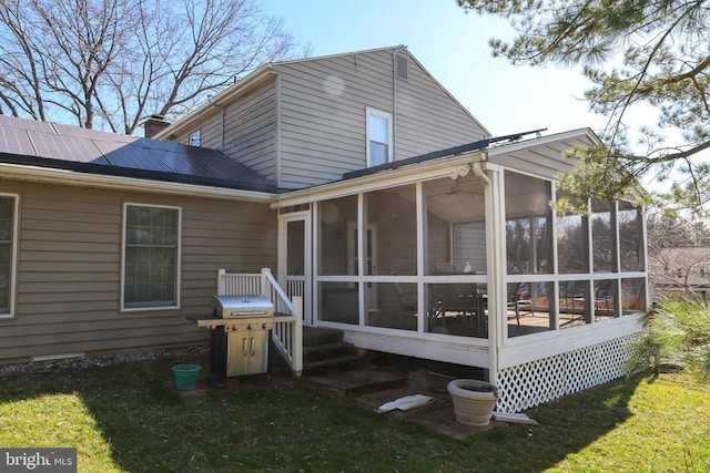 back of property featuring a lawn, solar panels, a chimney, and a sunroom