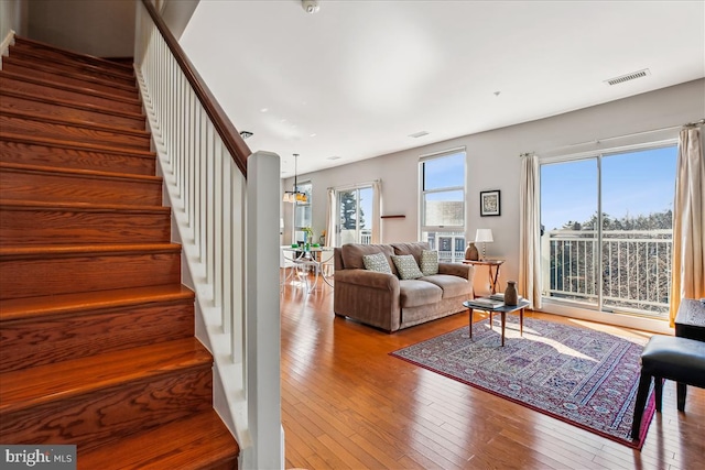 living room featuring stairway, wood-type flooring, and visible vents