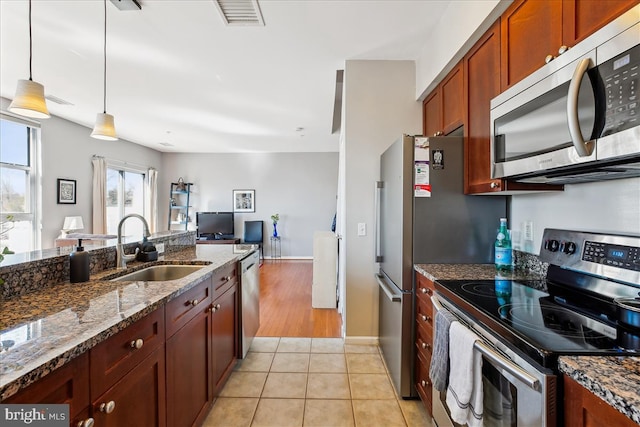 kitchen featuring light tile patterned floors, stainless steel appliances, a sink, visible vents, and decorative light fixtures