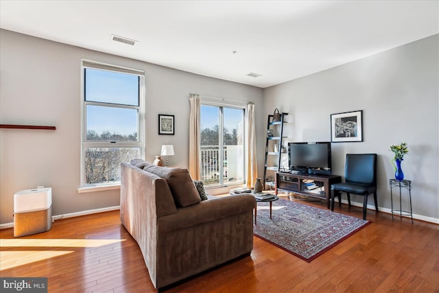 living area featuring wood-type flooring, visible vents, and baseboards