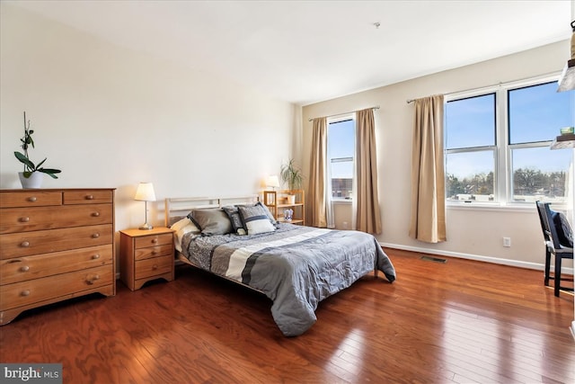 bedroom with hardwood / wood-style floors, visible vents, and baseboards