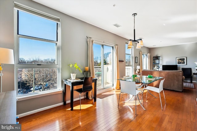 dining space with wood-type flooring, visible vents, and baseboards