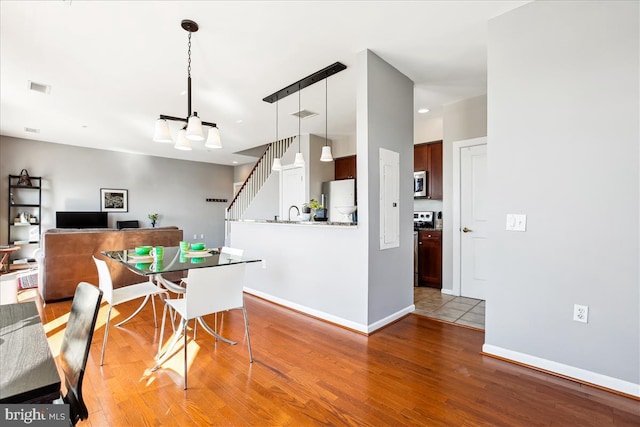 dining room with stairway, wood finished floors, visible vents, and baseboards