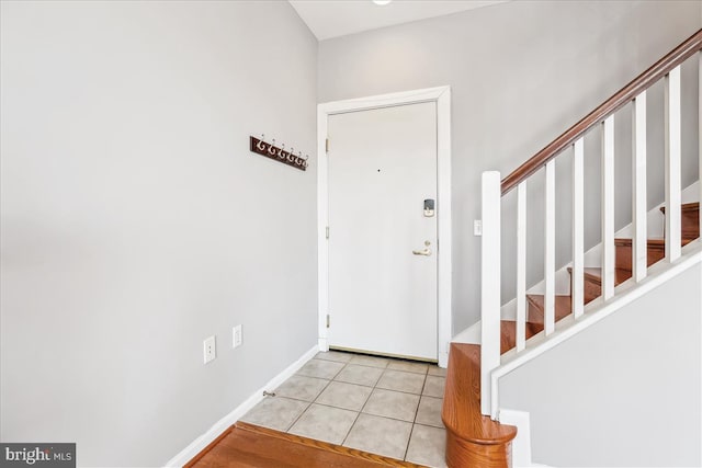 entryway with light tile patterned floors, baseboards, and stairway