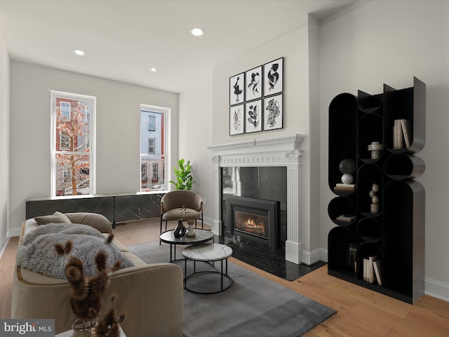 living room featuring recessed lighting, baseboards, light wood finished floors, and a tile fireplace