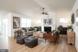 living room with baseboards, lofted ceiling, ceiling fan, wood finished floors, and a fireplace