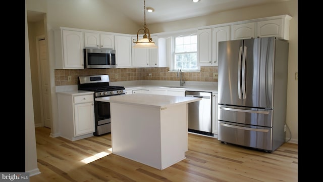 kitchen with a kitchen island, appliances with stainless steel finishes, light countertops, pendant lighting, and a sink