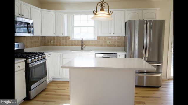 kitchen with a sink, stainless steel appliances, light countertops, and pendant lighting