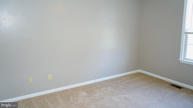 spare room with baseboards, visible vents, and light colored carpet