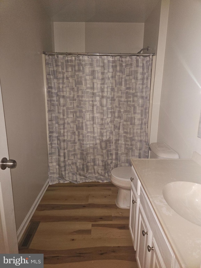 bathroom featuring visible vents, toilet, vanity, wood finished floors, and baseboards