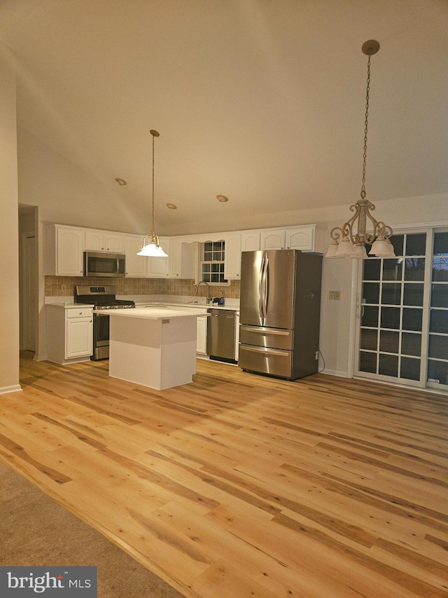 kitchen featuring stainless steel appliances, a kitchen island, white cabinets, light countertops, and decorative light fixtures