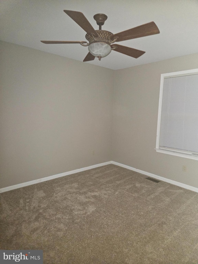 carpeted spare room with a ceiling fan, visible vents, and baseboards