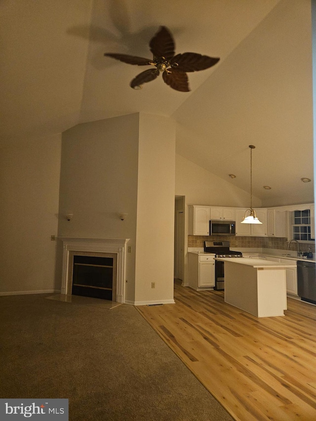 unfurnished living room with a ceiling fan, a fireplace with flush hearth, light wood-type flooring, high vaulted ceiling, and a sink