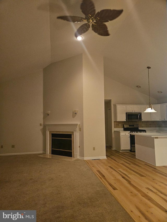 unfurnished living room featuring high vaulted ceiling, light wood-style flooring, a fireplace with flush hearth, a ceiling fan, and baseboards