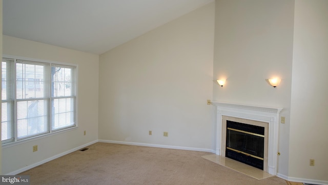 unfurnished living room with light carpet, a premium fireplace, visible vents, baseboards, and vaulted ceiling