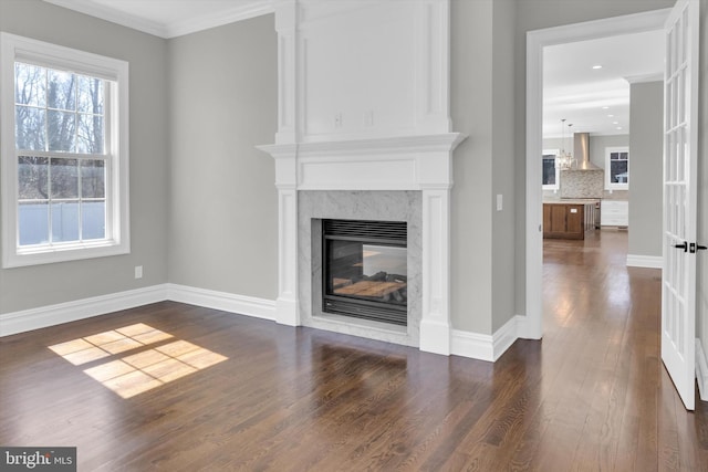 unfurnished living room featuring dark wood-style floors, crown molding, baseboards, and a premium fireplace