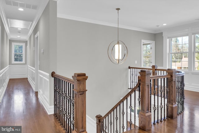corridor with dark wood-style floors, an upstairs landing, a decorative wall, and crown molding