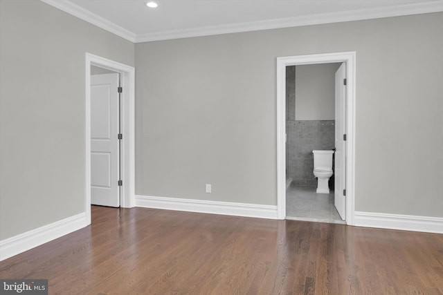 unfurnished bedroom featuring crown molding, baseboards, tile walls, and wood finished floors