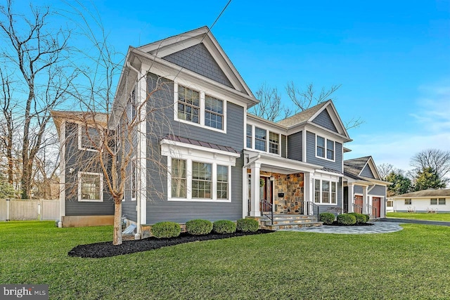 shingle-style home featuring a front yard and fence