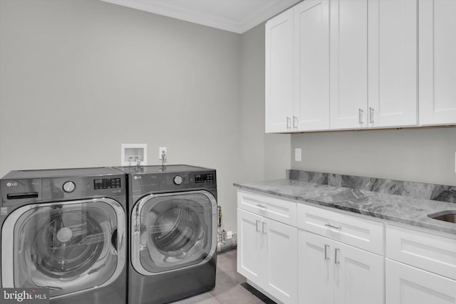 washroom featuring ornamental molding, washing machine and clothes dryer, and cabinet space