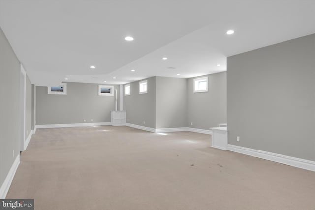 below grade area with light carpet, baseboards, and recessed lighting