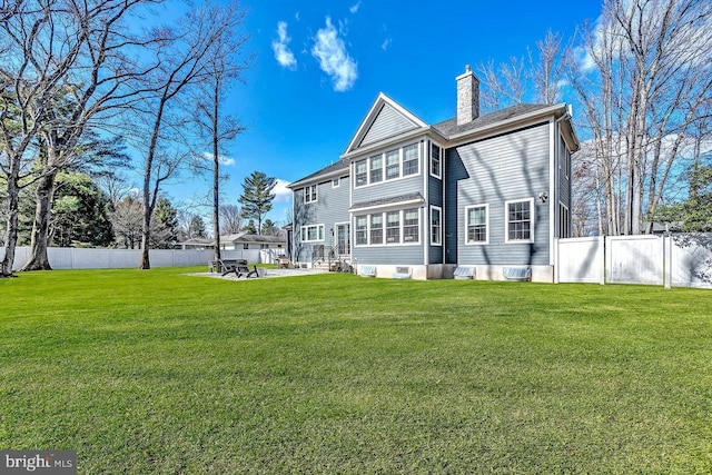 back of property featuring a patio area, a chimney, a fenced backyard, entry steps, and a yard