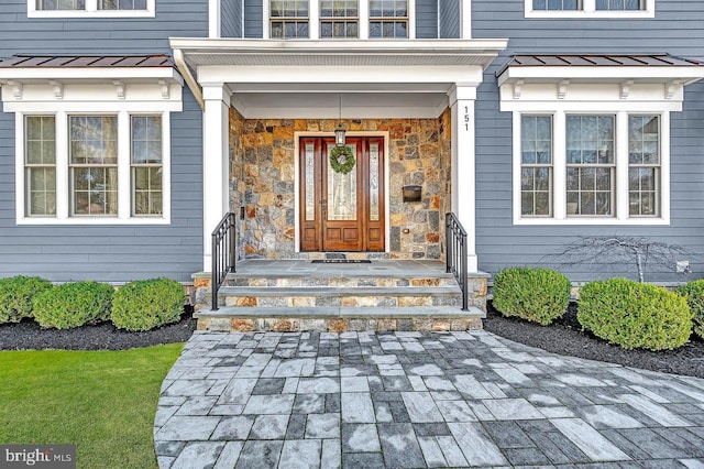 property entrance with a standing seam roof, stone siding, and metal roof