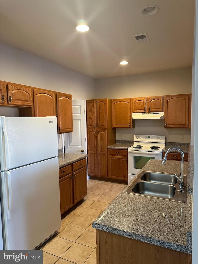 kitchen with brown cabinets, visible vents, a sink, white appliances, and under cabinet range hood