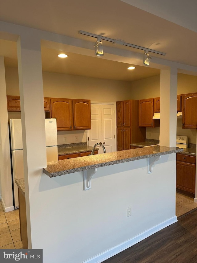 kitchen with a peninsula, a breakfast bar area, and brown cabinetry