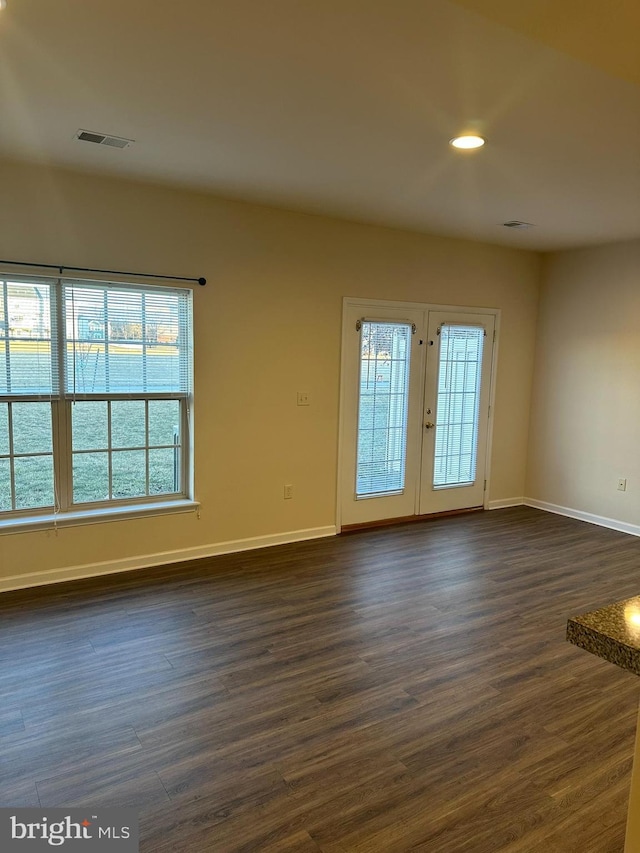 spare room featuring dark wood-type flooring, french doors, visible vents, and baseboards