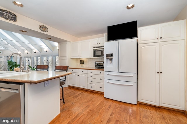 kitchen with a sink, white fridge with ice dispenser, white cabinets, and dishwasher