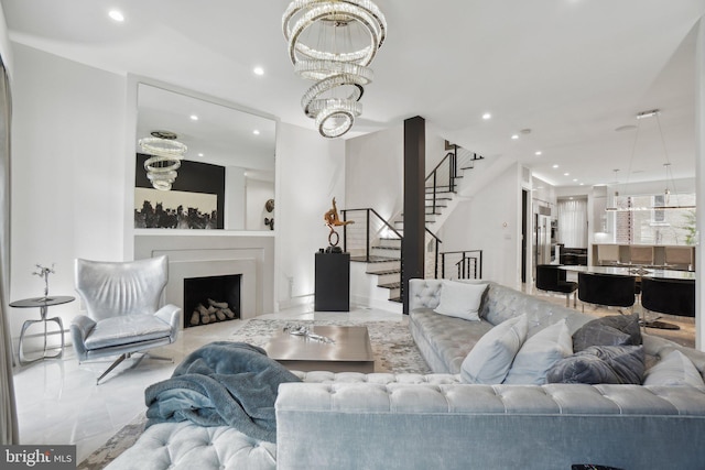 living room featuring marble finish floor, recessed lighting, an inviting chandelier, a fireplace, and stairs