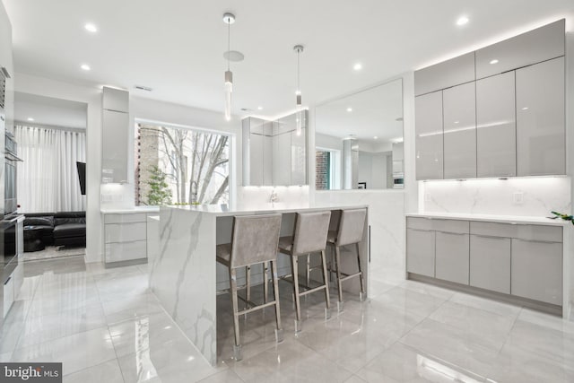 kitchen featuring visible vents, modern cabinets, gray cabinetry, recessed lighting, and a breakfast bar area