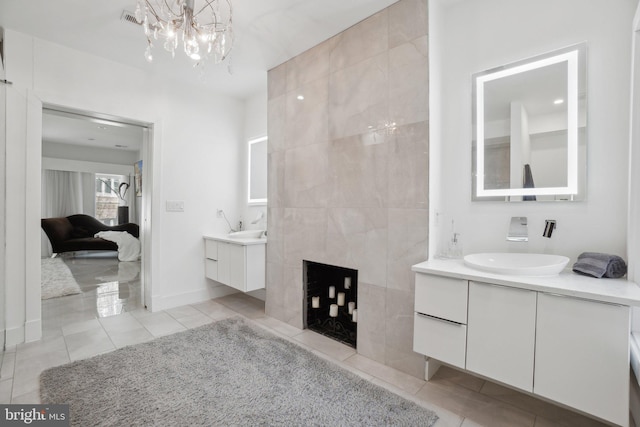 ensuite bathroom with two vanities, ensuite bathroom, a sink, a fireplace, and tile patterned flooring