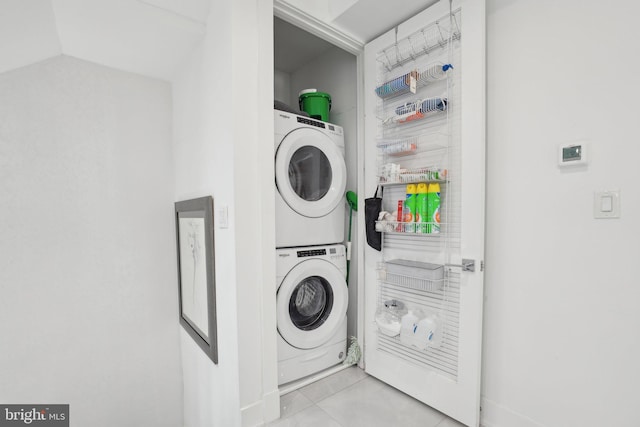 laundry area with tile patterned flooring, laundry area, and stacked washing maching and dryer