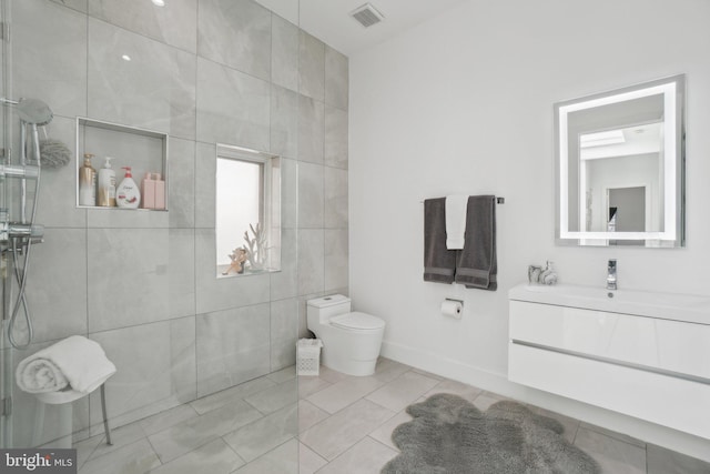 bathroom with visible vents, tiled shower, toilet, and vanity