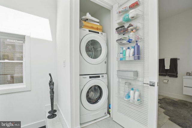 laundry area with baseboards, laundry area, and stacked washer / dryer