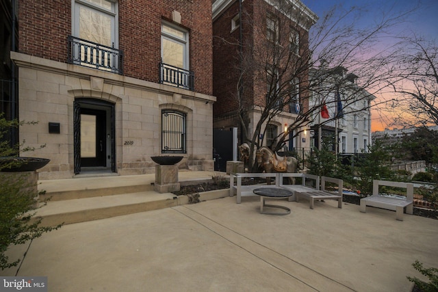 patio terrace at dusk featuring a balcony